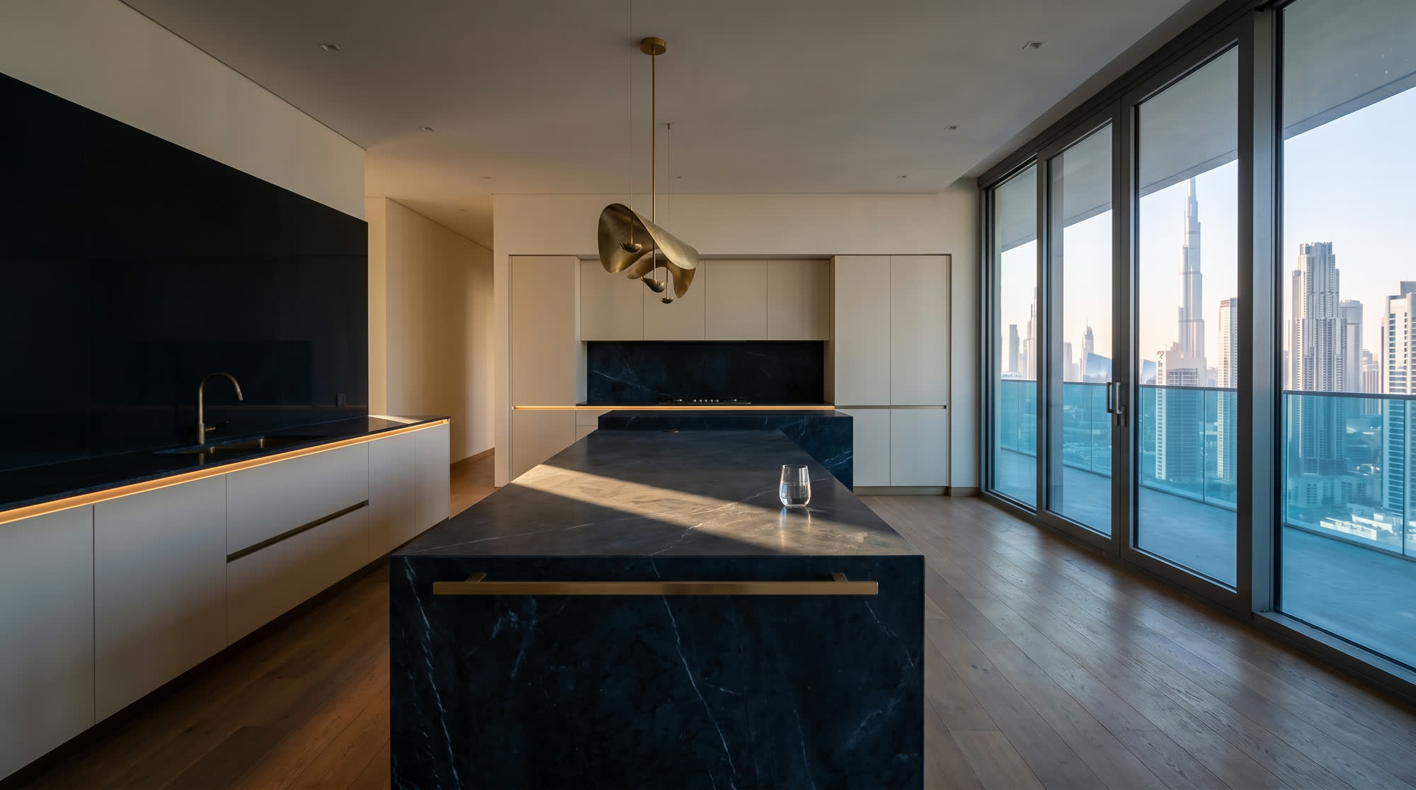 El mismo espacio ya terminado: isla de cocina en mármol, carpintería a medida y el skyline de Dubái por el ventanal